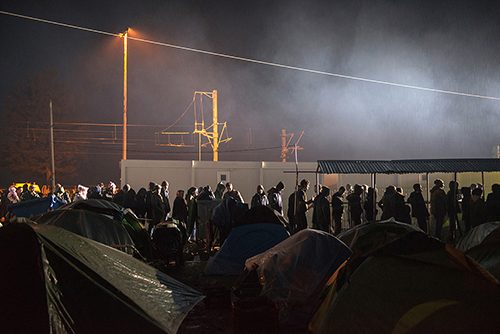 Refugees line up in the rain for food in Idomeni. Three times a day, thousands of people queue up be offered dry submarine sandwiches, biscuits and a boiled egg. Mothers stand in line to get their baby bottles filled with milk. Idomeni, March 23, 2016